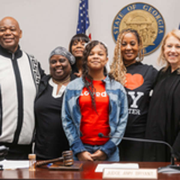 Mother and daughter gather at adoption day with loved ones and judge.